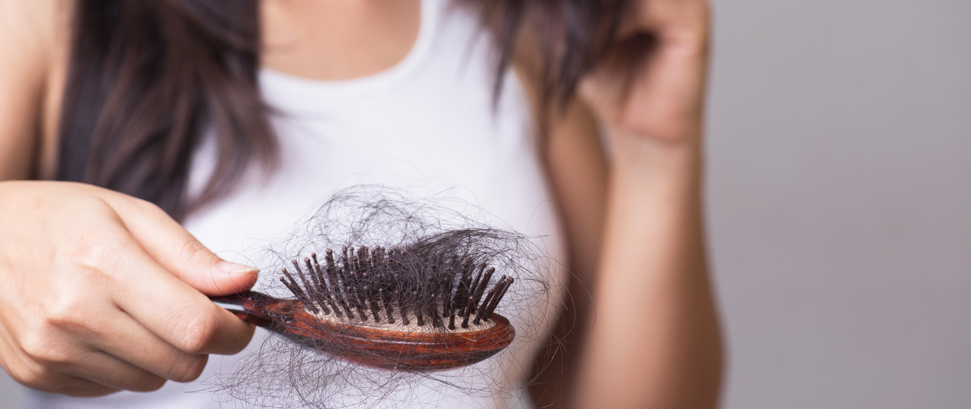 Mulher com uma escova de cabelo na m&atilde;o cheio de fios de cabelo, como resultado da queda de cabelo